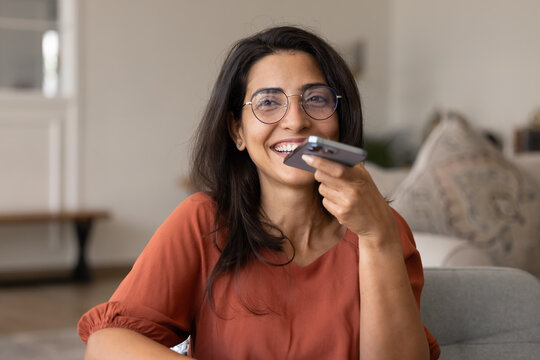 Happy beautiful Hispanic woman in elegant eyeglasses recording audio message