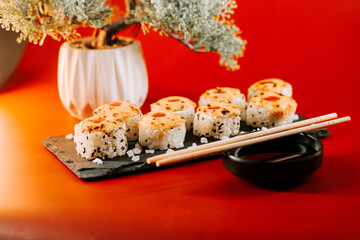 Delicious sushi rolls served on a stone platter with decorative plant and chopsticks