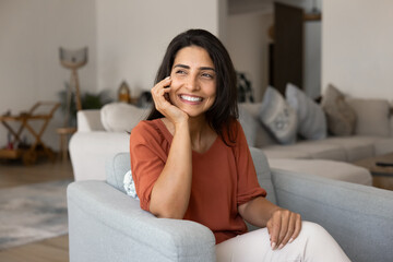 Happy young Hispanic homeowner woman enjoying being at cozy home
