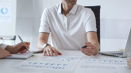 Professional team reviewing financial charts, collaborating intently around conference table in contemporary workspace, sharing insights during strategic planning session