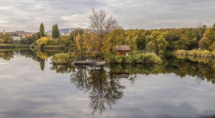 Fototapeta premium Small island with hut reflected in calm lake 