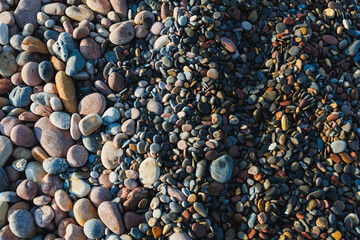 Colorful pebbles scattered on a beach during sunset create a stunning natural mosaic at the...