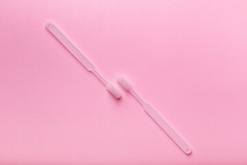 White toothbrushes from above on pink background. Oral care, gum and teeth health. Morning routine and health care.