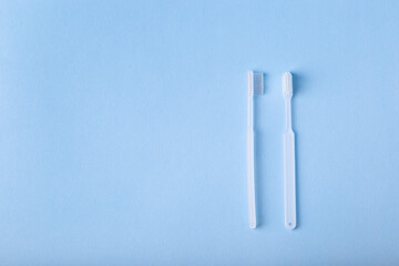 White toothbrushes from above on blue background. Oral care, gum and teeth health. Morning routine and health care.