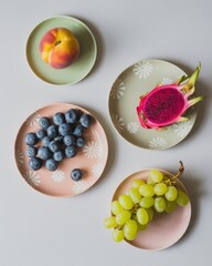 Flat lay of colorful fruits on patterned plates with white background peach blueberries