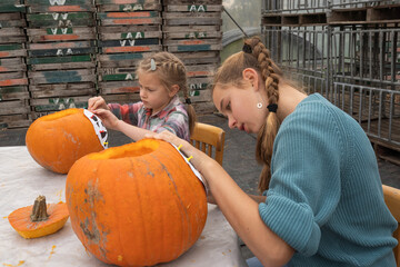 Young girl and teenager engaged in creative pumpkin carving activity, showcasing artistic skills and teamwork in a vibrant autumn setting with pumpkins and tools
