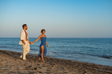 Romantic Couple Walking Along the Seashore at Sunset