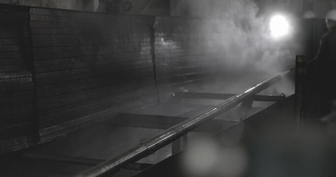 Industrial scene showcasing a long pipe being cleaned in a misty environment, with gradual camera zoom emphasizing the action and surrounding textures of the workspace