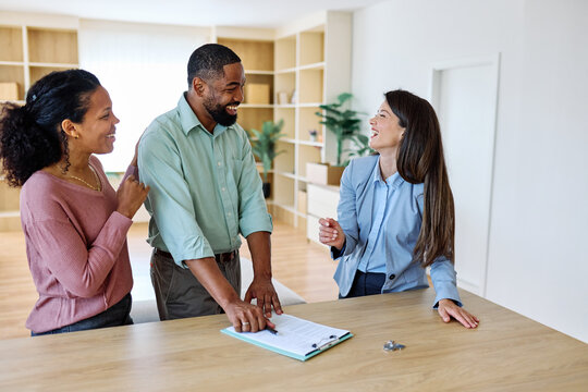 Female Real Estate Agent Selling And Showing The Modern Apartment To His Young Clients That Are Standing Next To Him In The Fancy Apartment