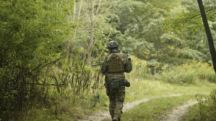 Camouflaged army soldier with AR15 carbine on a mission. Taking aim with the rifle. Military recon