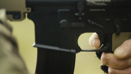 Soldier with AR15 carbine on a mission. Close-up finger pulling the trigger on the rifle. Military recon