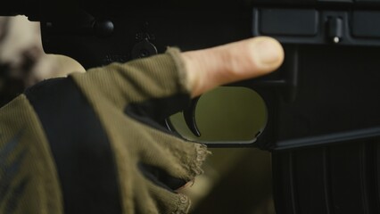 Soldier with AR15 carbine on a mission. Close-up finger pulling the trigger. Military recon