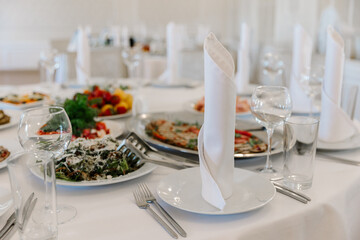 Close-up of an elegantly folded white napkin, plate, and crystal glasses on a banquet table ready for a formal dining event