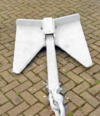 white painted steel anchor lies outside on the street