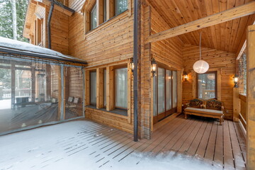 Cozy wooden cabin entrance surrounded by snow with a stylish outdoor seating area