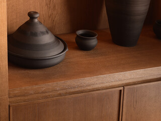 naturaltoned ceramic vessels on wooden cabinet illuminated by warm directional light creating cozy