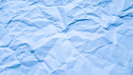 Full frame, high-angle view of wrinkled, crumpled light blue paper texture, creating an abstract...