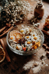 Dried flowers and spices in a glass bowl on a rustic wooden table
