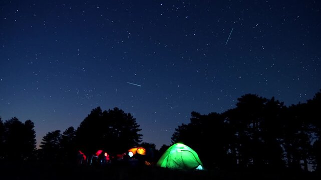 A peaceful time lapse of tents and campers under a star-filled night sky beside the forest. Perfect for outdoor, nature, and adventure-themed visuals.