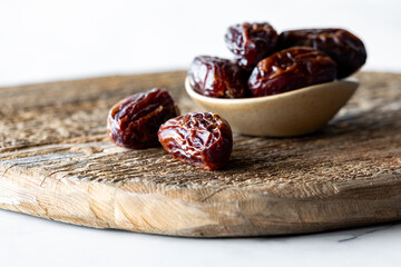 A close up view of whole medjool dates on a rustic wooden board.
