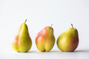 Whole Forelle pears standing in a row, against a light background.