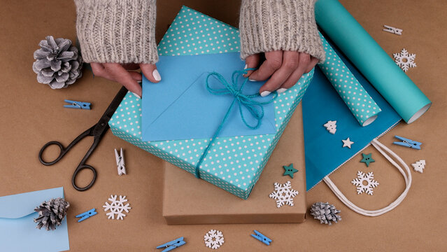 Woman packing Christmas gifts with blue paper