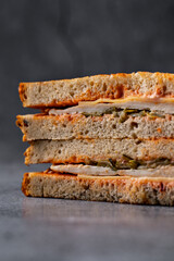 Layered grilled turkey and cheese sandwich with golden toast, served on a rustic stone backdrop