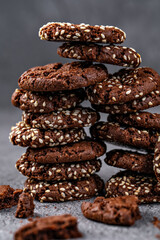 Stack of rich chocolate cookies with sesame seeds, presented on a textured surface