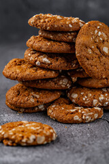 Golden oatmeal cookies stacked on a rustic surface with sesame seeds