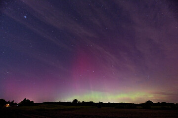 Aurora sky with pink and yellow glow above open field in Kollund, DK