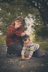 Fototapeta premium Adult man and his son training classic marbles outdoor on pathway in nature