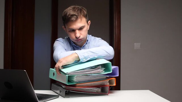 Tired man overwhelmed by office paperwork deadline