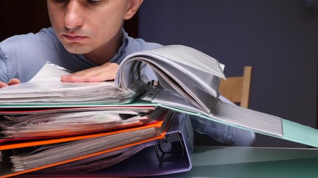 Man searching through stack of business binders and files