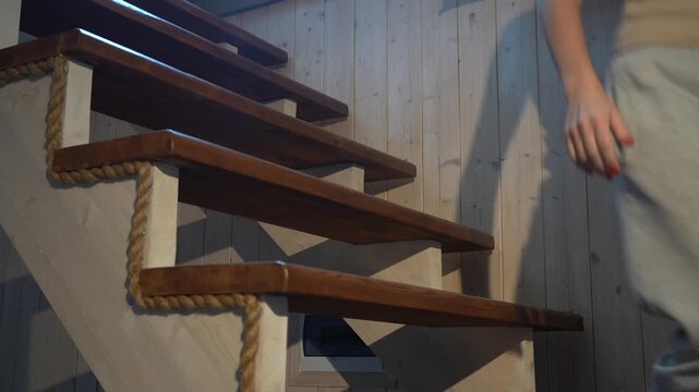 A beautiful young woman descending the stairs in a country house. Close-up of her legs.