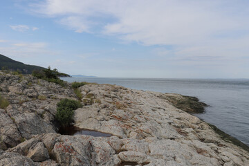 View of the coast of a vast river with an horizon. Riverside in rock in Charlevoix and geological transformation and pot. Tourism in Charlevoix in Quebec.