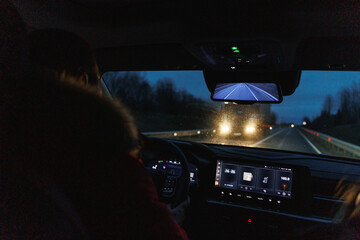 driver navigating rainy city roads, night journey with illuminated dashboard and tense urban