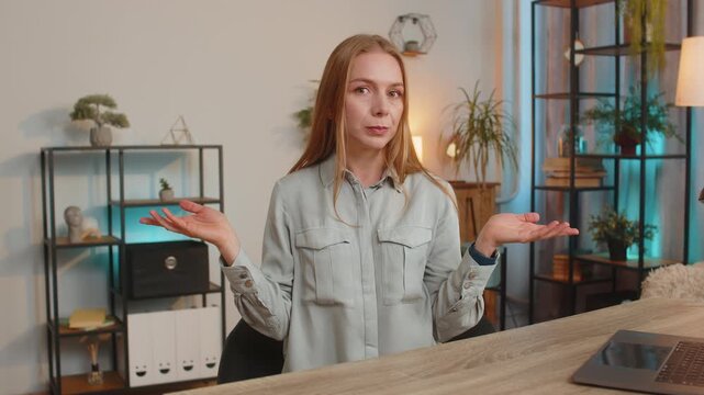 I dont know what to say. Confused woman feeling embarrassed about ambiguous question, having doubts, no answer idea, being clueless, uncertain. Caucasian blonde girl sitting at home office desk table.