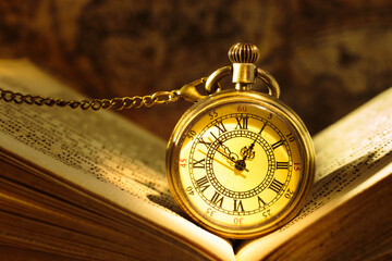 Vintage pocket watch with old book on a map background.