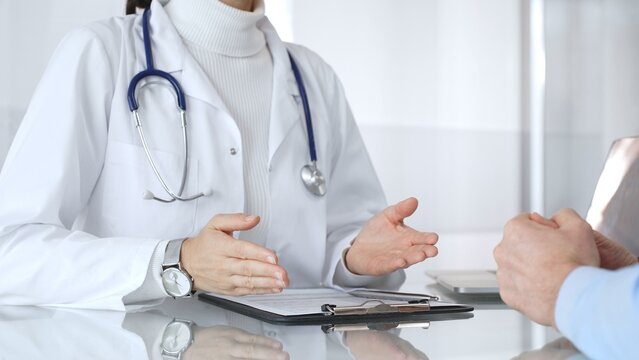 Doctor consulting patient, discussing medical information during a healthcare appointment at the clinic. Medicine, healthcare and science concept