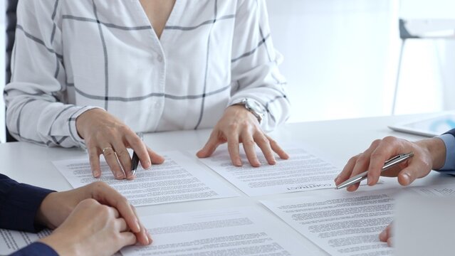 Business professionals or lawyers sitting at the desk in a bright office, reviewing and discussing contract papers. Teamwork concept - Powered by Adobe