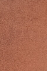 Close-up of a textured, warm terracotta-colored wall surface, showcasing its unique rough pattern and earthy tones. Copy space
