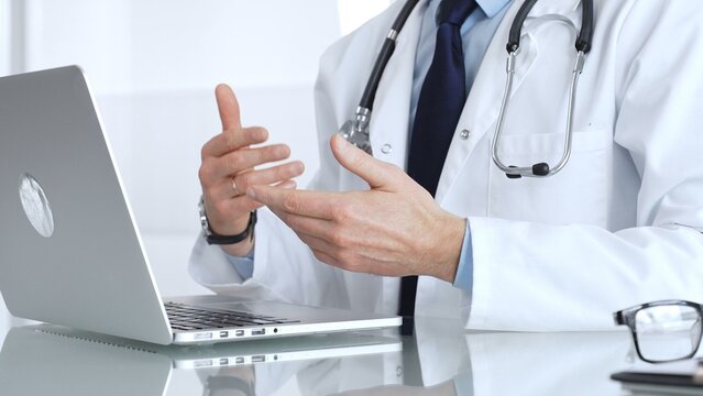 Doctor in white coat and stethoscope providing virtual medical consultation, discussing health issues with a patient online. Medicine, healthcare and science concept