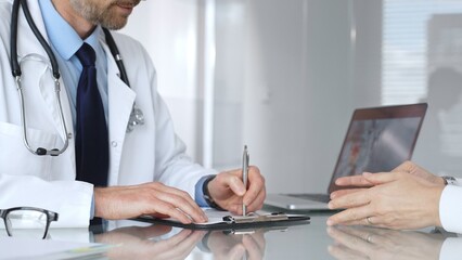Doctor in a white lab coat and stethoscope consulting a patient, discussing test results and providing medical advice. Medicine, healthcare and science concept
