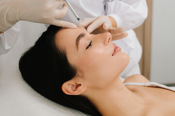 Glabellar Botulinum Toxin Injection close-up. Anti-wrinkle therapy using botulinum toxin smooths deep creases. Non-surgical botulinum toxin treatment for the forehead area.