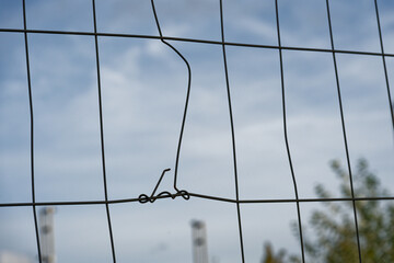 A wire mesh fence panel with a snapped rod wrapped