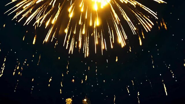 Golden, star-like fireworks exploding and falling in the dark night sky. Excellent for celebration, New Year's Eve, event openers, and holiday backgrounds.
