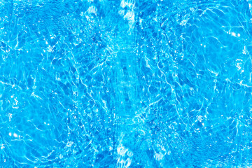 Blue water with ripples on the surface. Defocus blurred transparent blue colored clear calm water surface texture with splashes and bubbles. Water waves with shining pattern texture background.
