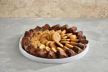 Assorted cookies and brownies arranged neatly on a round platter.