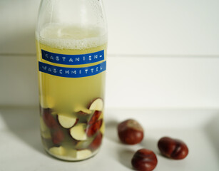 Homemade natural detergent made from horse chestnuts in a glass bottle with liquid, sustainable eco-friendly cleaning concept