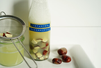 Homemade natural detergent made from horse chestnuts in a glass bottle with liquid, sustainable eco-friendly cleaning concept